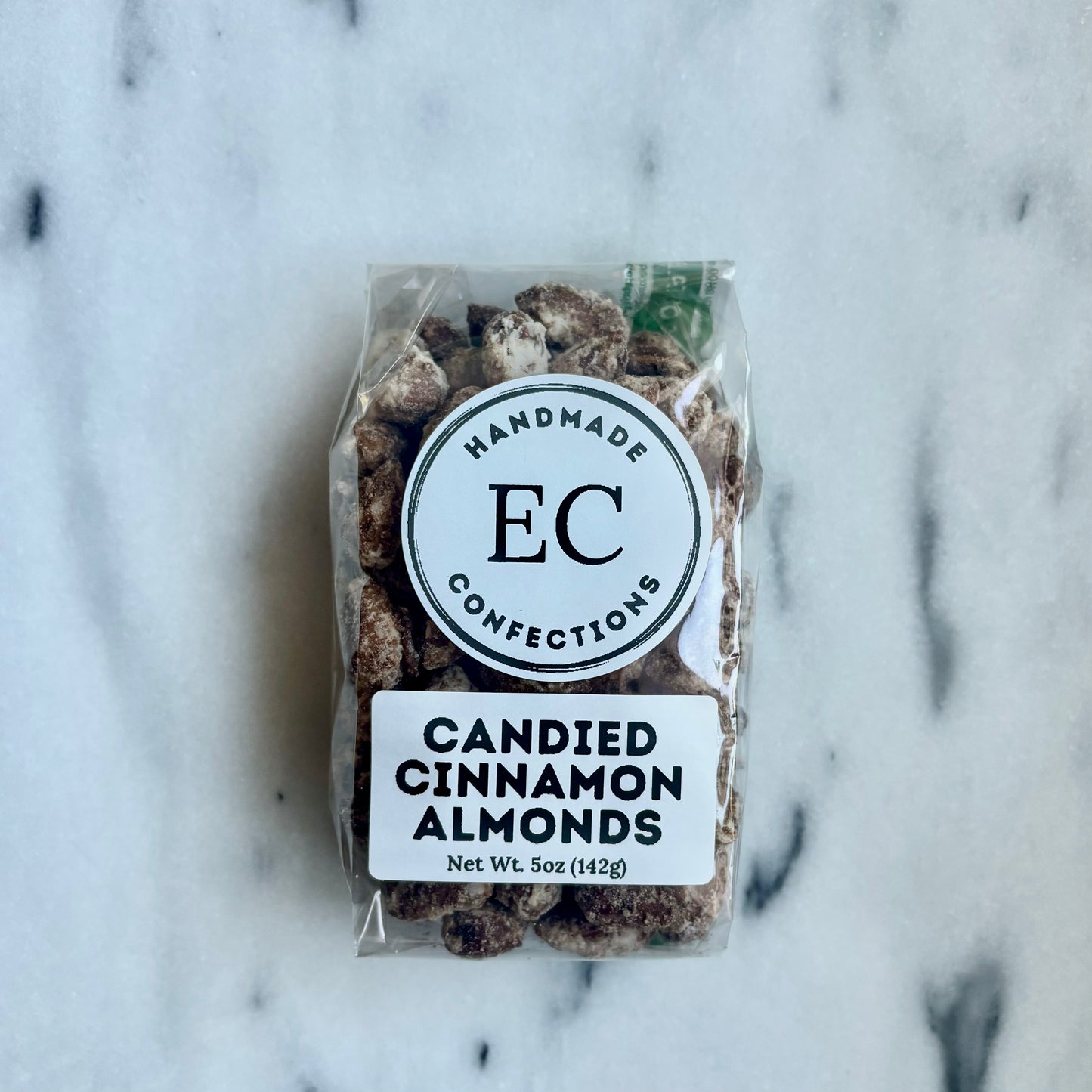 Packaged candied cinnamon almonds with 'EC Confections' label on a marble background