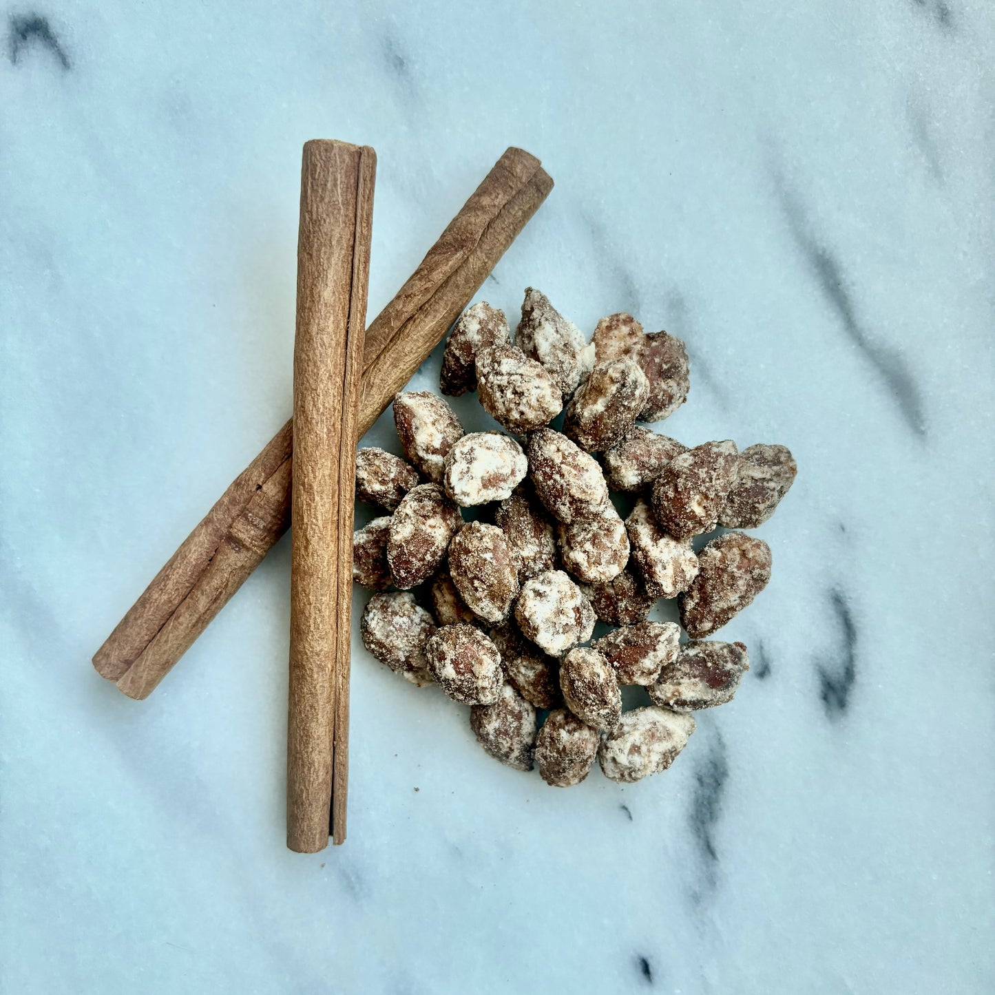 Cinnamon sticks and sugared almonds on a marble surface